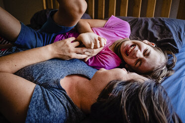 High angle view of happy mother with daughter lying on bed at home - CAVF49297