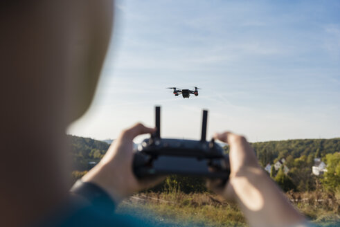 Junge steuert eine fliegende Drohne im Freien - DIGF05137