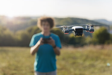 Boy navigating a flying drone outdoors - DIGF05139