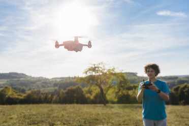 Junge steuert eine fliegende Drohne im Freien - DIGF05141
