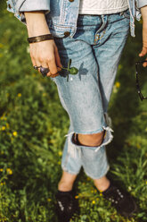 Tiefschnitt einer Frau in zerrissenen Jeans, die auf einer Wiese im Park steht - CAVF49356