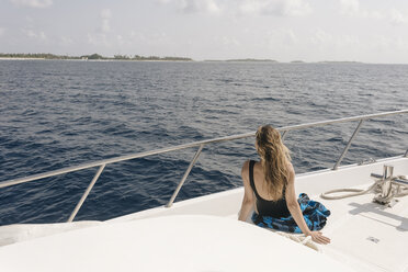 Rear view of woman looking at sea while traveling in yacht against sky during sunny day - CAVF49384