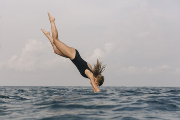 Side view of woman diving into sea against sky - CAVF49385