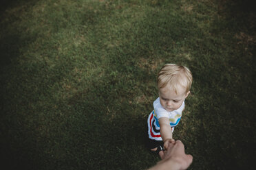 Ausgeschnittenes Bild einer Mutter, die die Hände ihres Sohnes auf einer Wiese im Park hält - CAVF49515