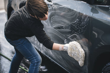 Seitenansicht eines Jungen beim Autowaschen in der Einfahrt - CAVF49533