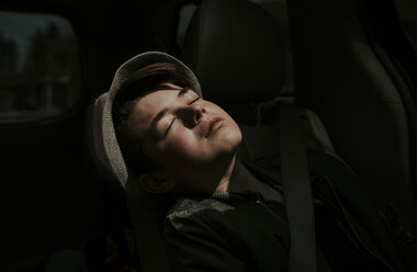 Close-up of boy with eyes closed sitting in car - CAVF49537