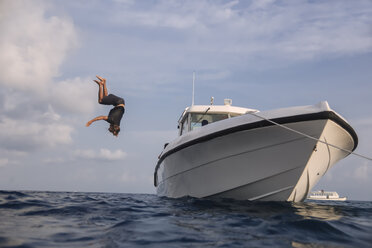 Niedriger Blickwinkel von Mann taucht ins Meer von Yacht gegen bewölkten Himmel auf den Malediven - CAVF49589