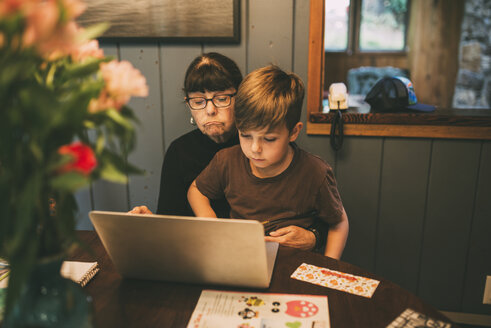 Enkel lehrt Großmutter die Benutzung eines Laptops auf dem Tisch zu Hause - CAVF49592