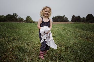 Portrait of happy girl holding fabric while standing on grassy field against sky at park - CAVF49613