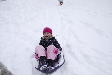 High angle view of cheerful girl sitting on sled during winter - CAVF49635