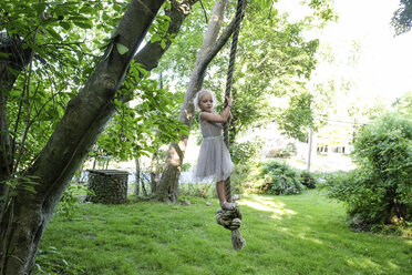 Nettes Mädchen schaut weg, während sie auf einer Seilschaukel im Hof schwingt - CAVF49636