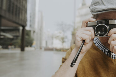 Close-up of man photographing with camera while standing on city street - CAVF49644