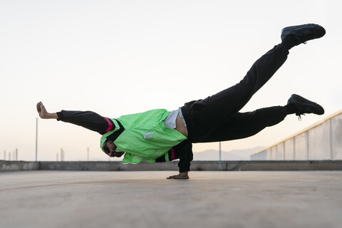 Mann tanzt Breakdance in städtischem Betongebäude, auf der Hand stehend, lizenzfreies Stockfoto