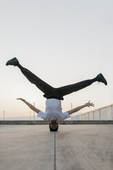 Man doing breakdance in urban concrete building, standing on head - JRFF01917