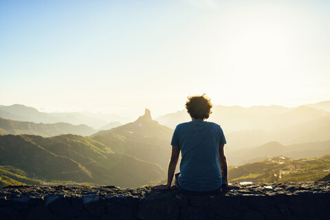 Spanien, Kanarische Inseln, Gran Canaria, Rückenansicht eines Mannes beim Betrachten einer Berglandschaft, lizenzfreies Stockfoto