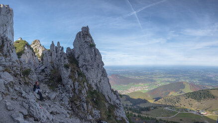 Deutschland, Oberbayern, Aschau, Wanderin auf dem Aussichtspunkt der Kampenwand sitzend - HAMF00512