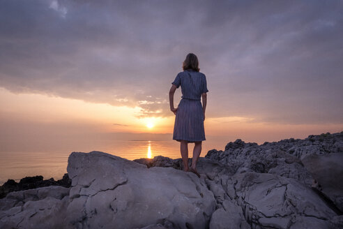 Kroatien, Istrien, Losinj, Frau steht bei Sonnenuntergang an der Felsenküste - HAMF00519