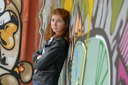 Italy, Finale Ligure, portrait of redheaded teenage girl leaning against mural - LBF02123