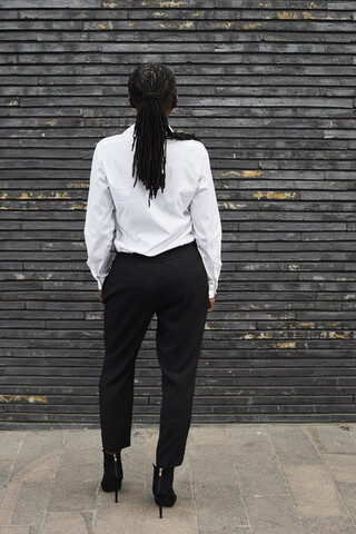 Back view of businesswoman with dreadlocks wearing white shirt and black trousers stock photo