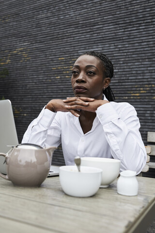 Porträt einer nachdenklichen Geschäftsfrau auf der Terrasse eines Cafés, lizenzfreies Stockfoto
