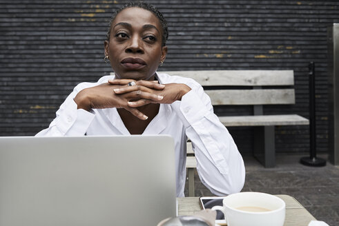 Portrait of pensive businesswoman sitting on terrace of a coffee shop - IGGF00684