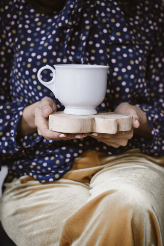 Frauenhände halten Holzbrett mit weißer Teetasse, Nahaufnahme, lizenzfreies Stockfoto