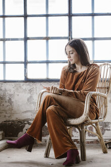 Fashionable young woman sitting on basket-chair in a loft - ALBF00658