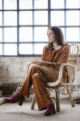 Fashionable young woman sitting on basket-chair in a loft - ALBF00659