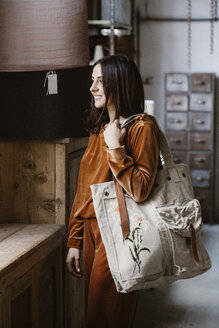 Lächelnde, modische junge Frau mit großer Einkaufstasche in einem Loft - ALBF00661