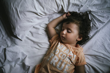 Ein kleines Mädchen schläft auf einem Bett mit einem T-Shirt mit der Botschaft 