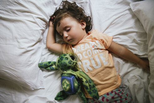 Ein kleines Mädchen schläft auf einem Bett mit einem T-Shirt mit der Botschaft 