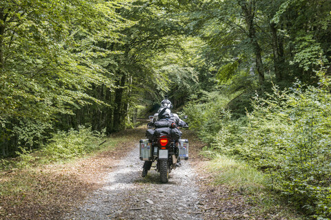 Vater und Sohn bei einer Motorradtour auf einer Waldpiste, lizenzfreies Stockfoto