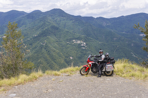 Italien, Toskana, Pistoia, Vater und Sohn machen eine Pause am Aussichtspunkt während einer Motorradtour, lizenzfreies Stockfoto