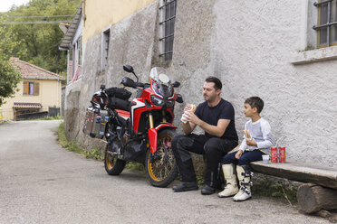 Vater und Sohn machen eine Mittagspause während einer Motorradtour - FBAF00147