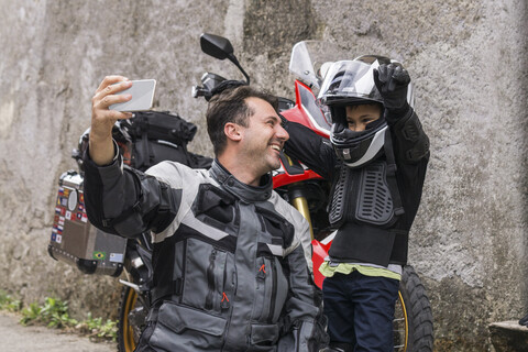 Glücklicher Vater und Sohn machen ein Selfie auf einer Motorradtour, lizenzfreies Stockfoto