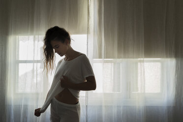 Young woman standing in front of window in white underwear - JPTF00025