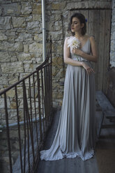 Junge Frau in grauem Kleid hält eine Blume - ALBF00670