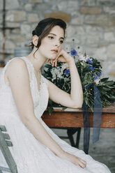 Nachdenkliche junge Frau im Hochzeitskleid sitzt am Tisch - ALBF00683