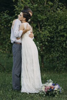 Bride and groom standing on meadow embracing - ALBF00691