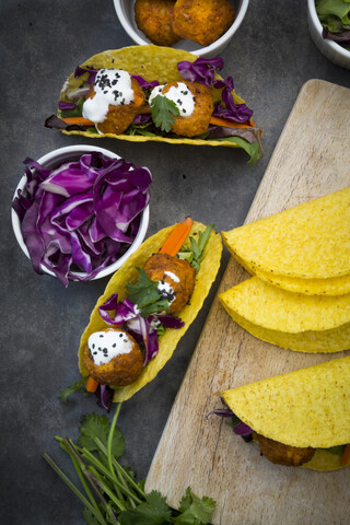 Süßkartoffel-Falafel in Taco-Shells, mit Rotkohl, Salat, Karotten, Joghurtsauce und schwarzem Sesam, lizenzfreies Stockfoto