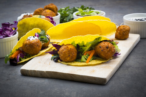 Süßkartoffel-Falafel in Taco-Shells, mit Rotkohl, Salat, Karotten, Joghurtsauce und schwarzem Sesam, lizenzfreies Stockfoto