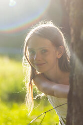 Porträt eines lächelnden Mädchens in der Natur bei Gegenlicht - SARF03951