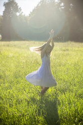 Happy girl dancing on summer meadow at backlight - SARF03953