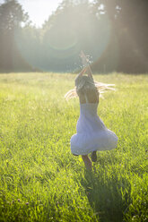 Glückliches Mädchen tanzt auf Sommerwiese im Gegenlicht - SARF03954