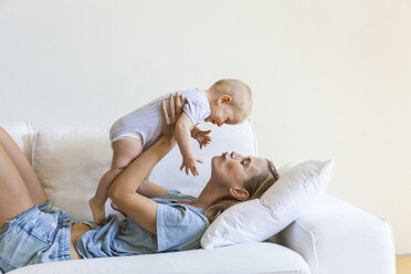 Mother lying on couch holding her baby girl - TCF05859