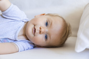 Portrait of blond baby girl lying on couch - TCF05876