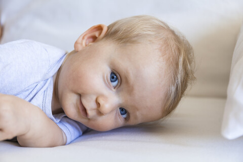 Porträt eines blonden kleinen Mädchens auf der Couch liegend, lizenzfreies Stockfoto