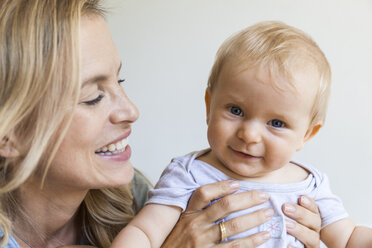 Porträt eines glücklichen kleinen Mädchens, das von seiner Mutter gehalten wird - TCF05881