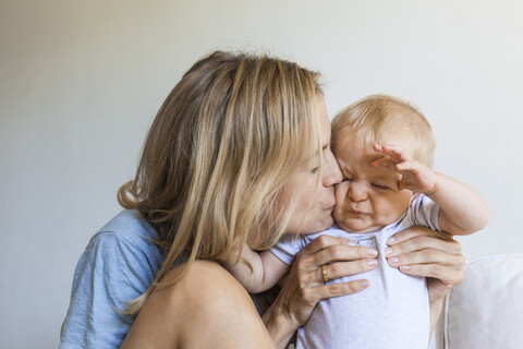 Mutter küsst ihr grimassierendes kleines Mädchen, lizenzfreies Stockfoto