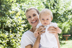 Portrait of happy mother holding her baby girl outdoors - TCF05884